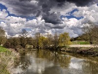April Showers  During the morning that this was shot, I think every one of those shower clouds off-loaded its cargo on me. I had not brought a coat or umbrella with me, either! The riverside willow trees were just beginning to green. £190